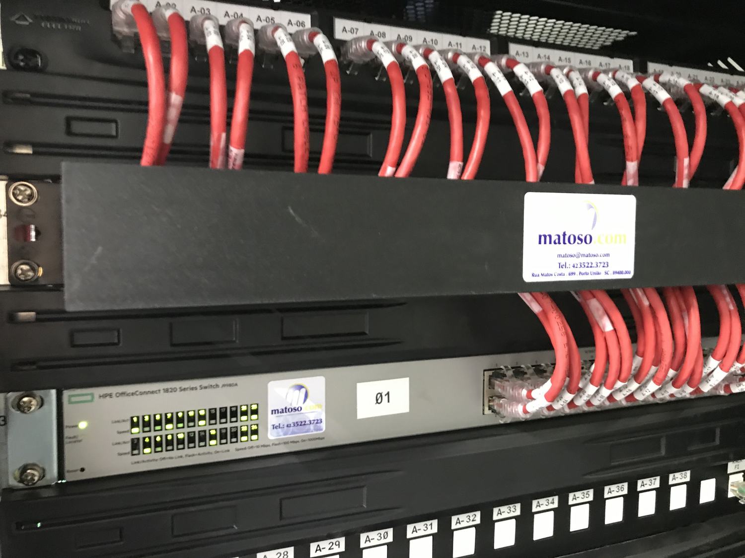 Patch panel com cabeamento vermelho e etiquetas A-01 a A-38, switch HPE OfficeConnect identificado