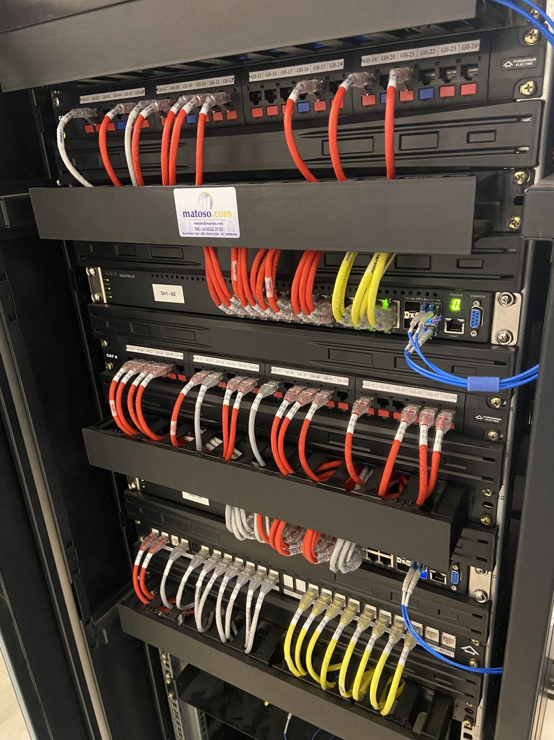 Rack industrial completo com switches empilhados e cabeamento identificado
